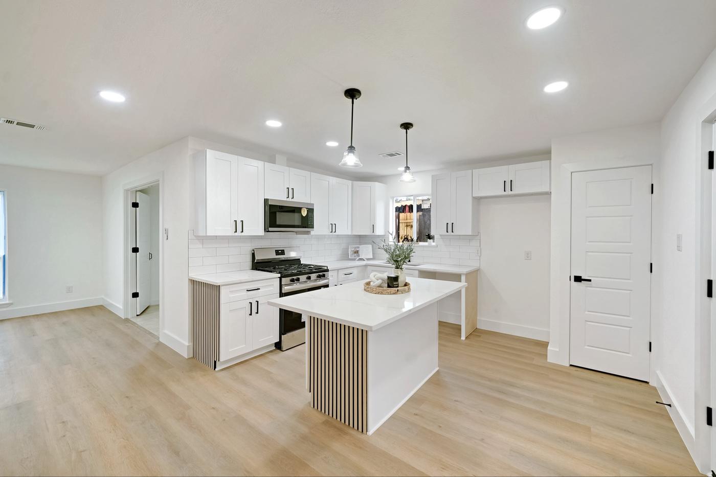 White kitchen with a fluted island, pendant lights, and stainless range