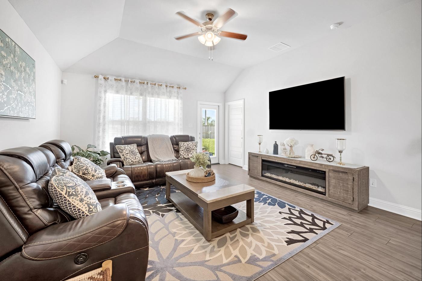 Living room with a leather sectional, wall-mounted television, and vaulted ceiling