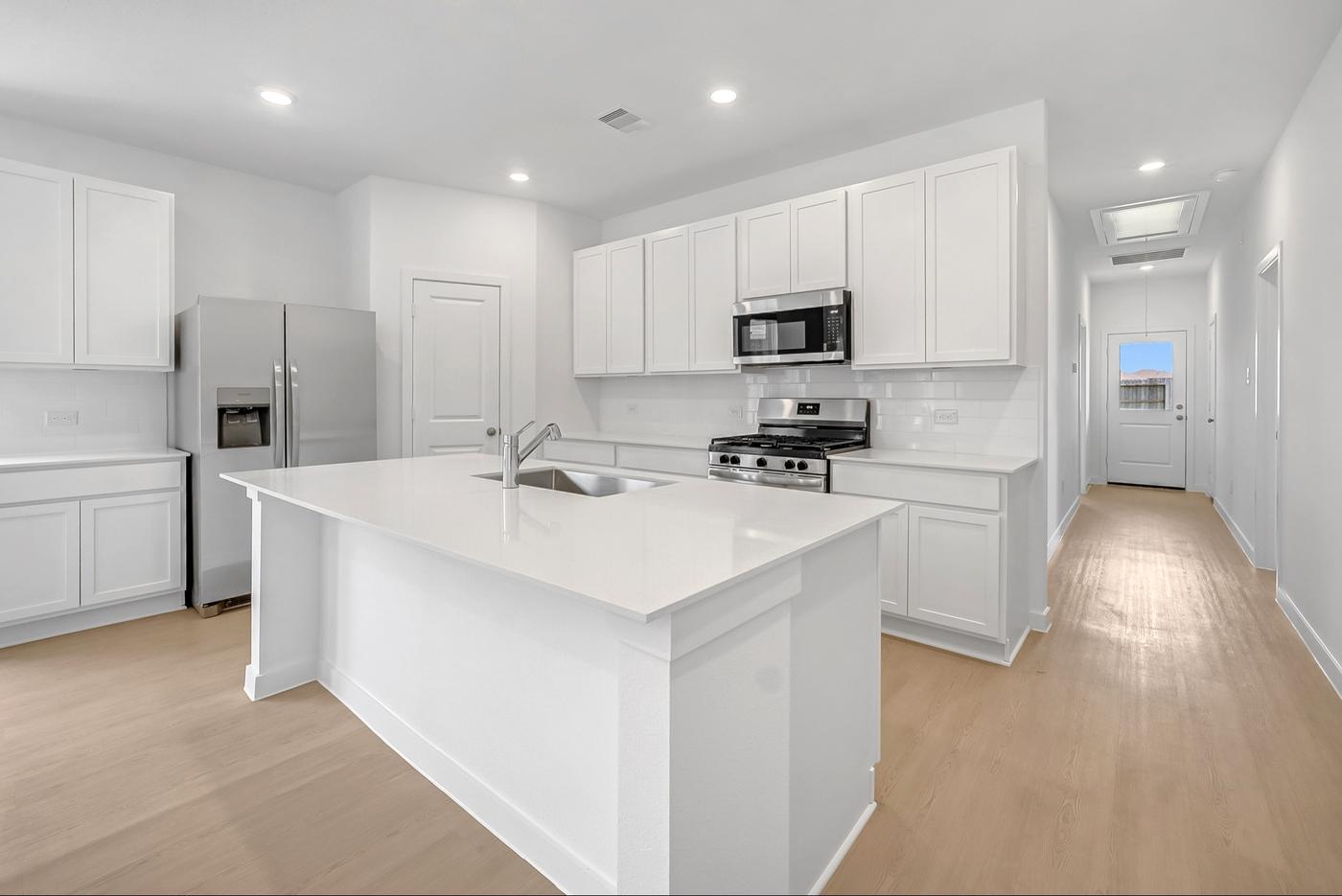 New construction kitchen with white shaker cabinets, quartz island, and stainless appliances