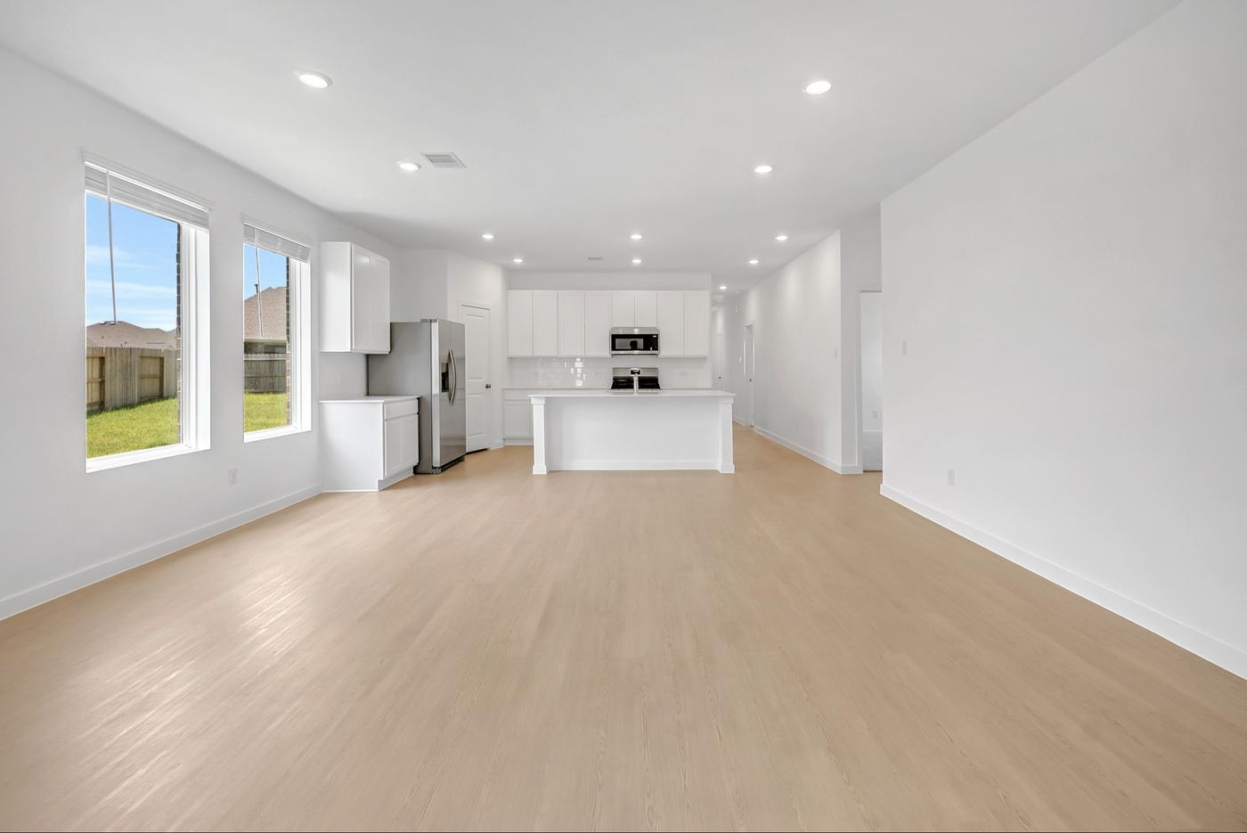 Empty open-plan living area in a new build looking toward the kitchen and back window